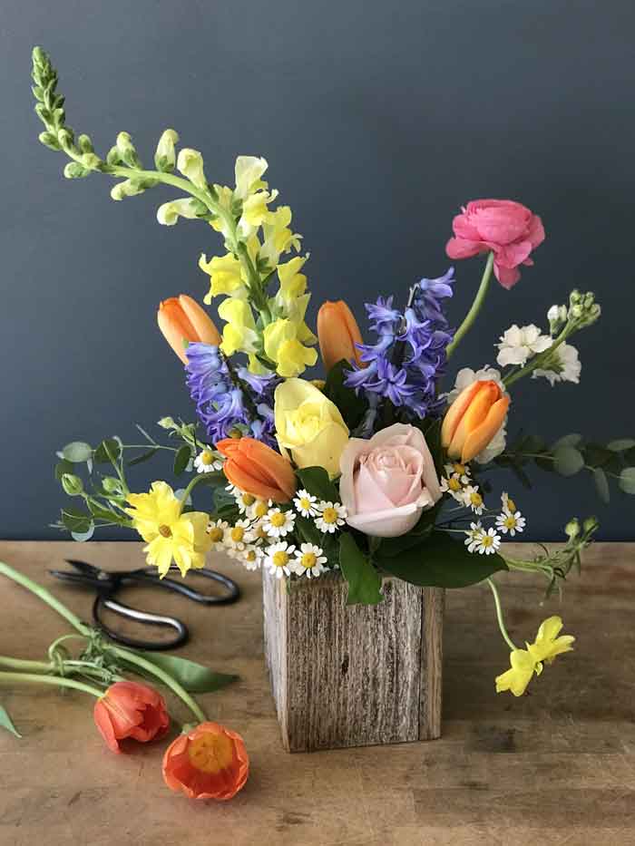 colorful spring freesias, tulips, hyacinths, and ranunculus in a wood box